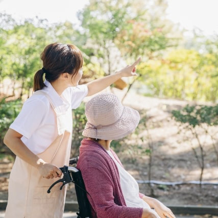 入居者が職員と共に屋外で過ごす様子。季節の自然を楽しむ生活風景。